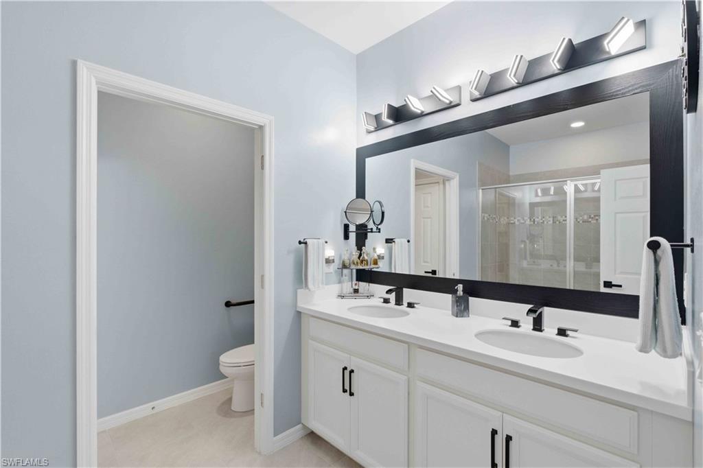 Double vanity featuring white cabinetry with black hardware, white countertops, and dual undermount sinks with matte black faucets