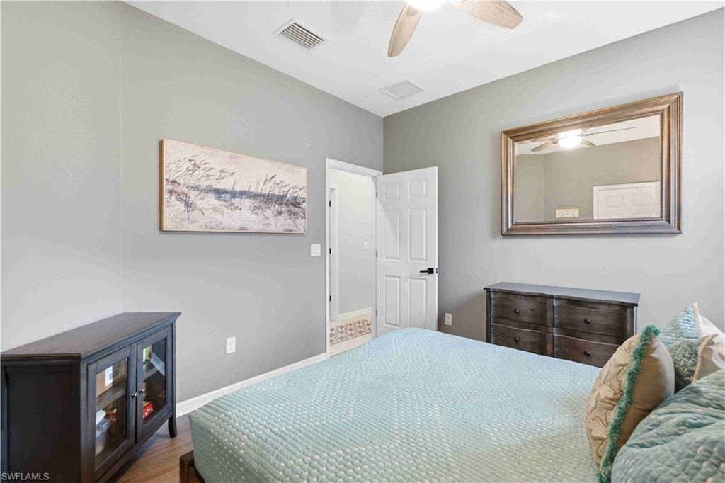 Spacious room featuring wood-finish flooring, a ceiling fan with light fixture, and light gray wall paint