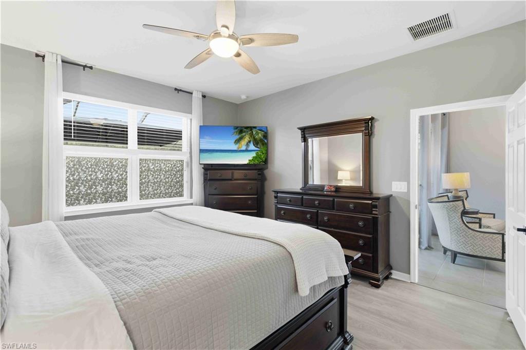 Bedroom featuring light grey walls, a ceiling fan with integrated lighting, and wood-finish flooring