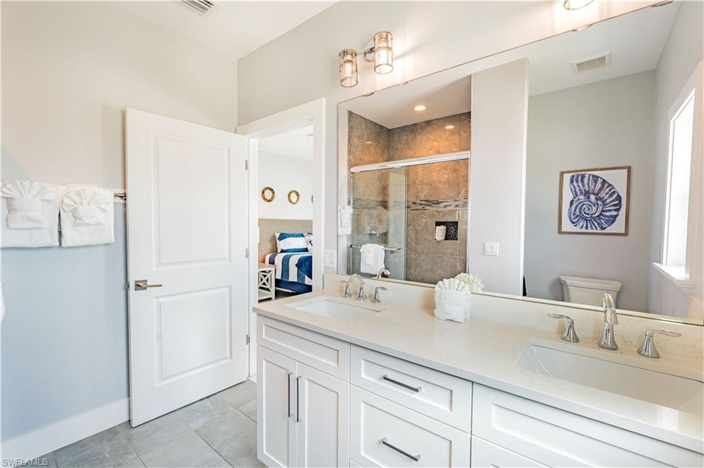 Dual vanity with light-toned countertop, white cabinetry, and brushed nickel hardware - Virtually Edited Image