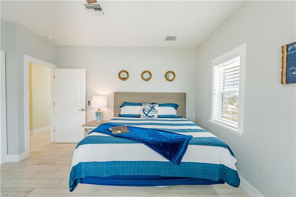 Bedroom featuring light wood-finish flooring, a white trim window with horizontal blinds, and a built-in ceiling light - Virtually Edited Image