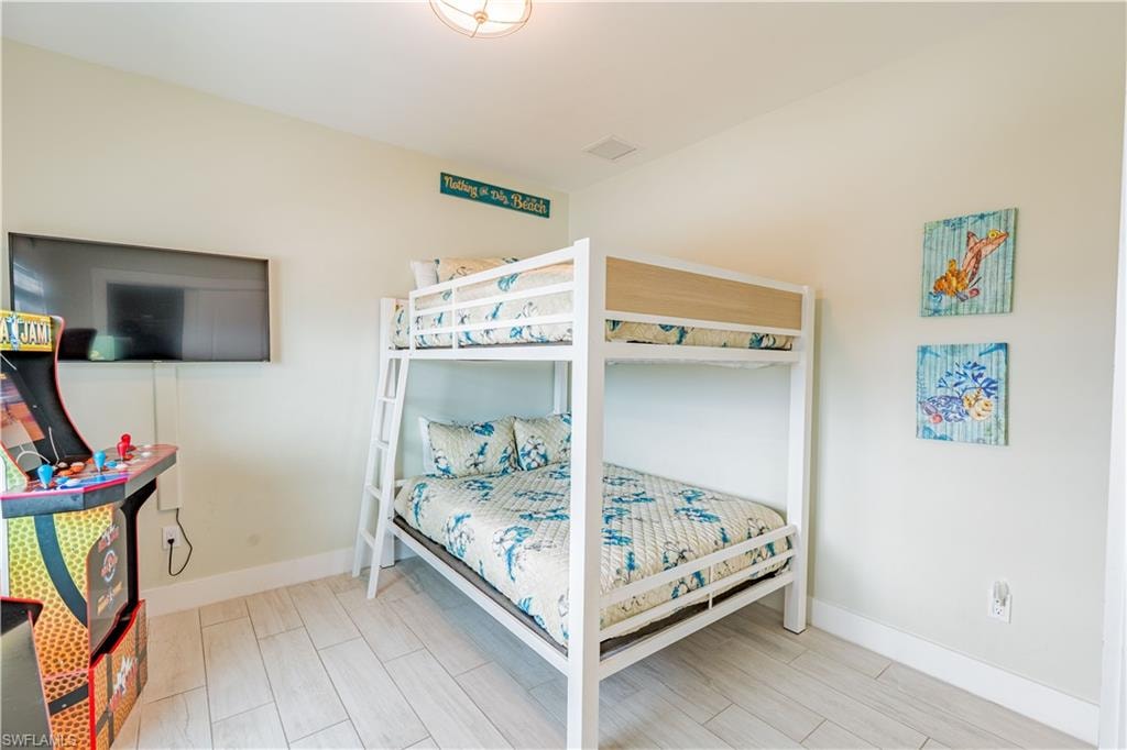 Bedroom featuring a bunk bed with integrated ladder, light-toned wood-finish flooring, recessed lighting, and a wall-mounted flat-screen television