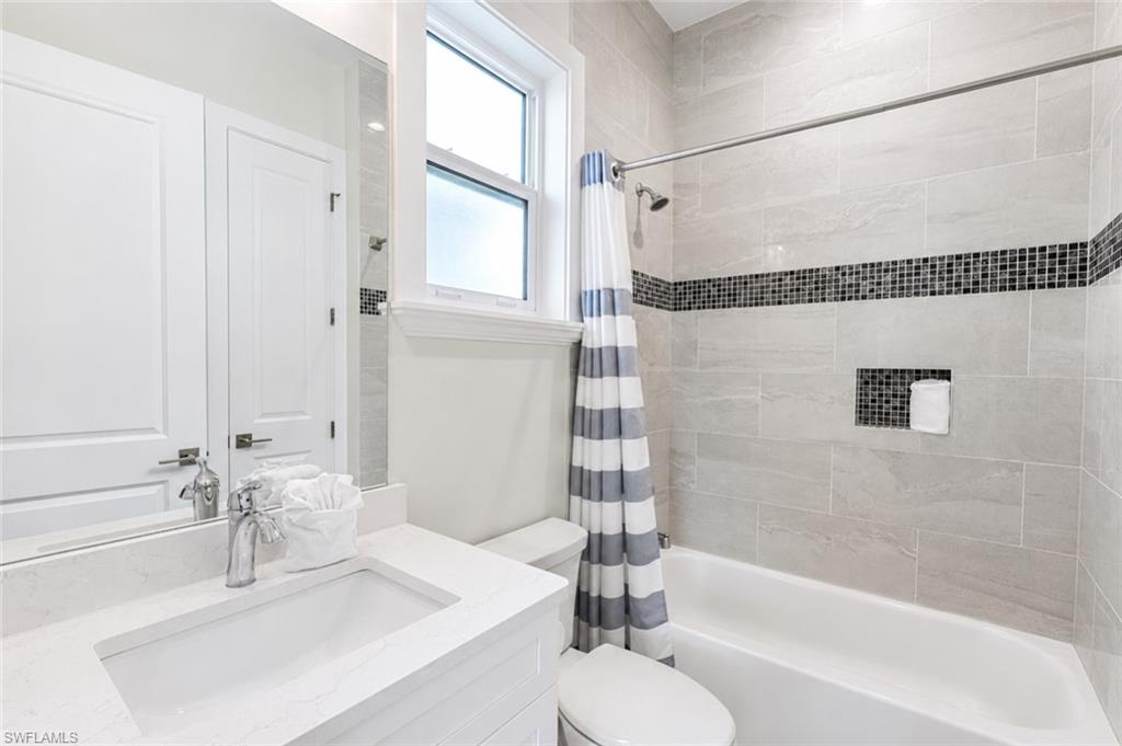 Bathroom featuring a white vanity with integrated sink, chrome faucet, and full-width mirror - Virtually Edited Image
