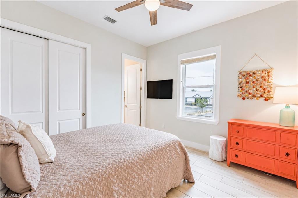 Bright room featuring wood-finish flooring, a ceiling fan, and a window with a woven shade - Virtually Edited Image