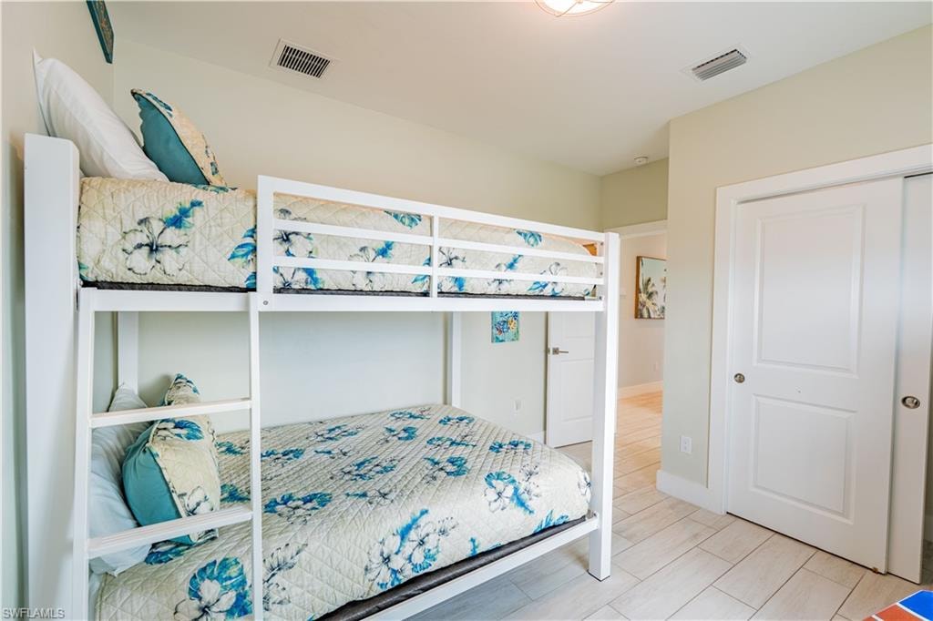 White bunk beds with integrated ladder, light-toned walls, recessed lighting, and wood-finish flooring - Virtually Edited Image