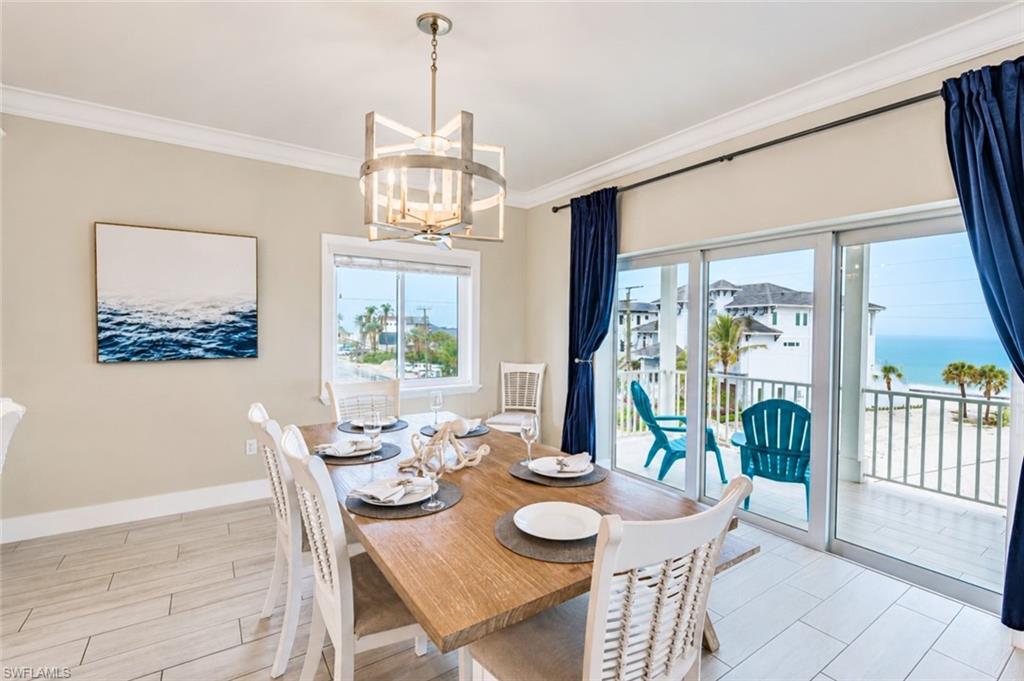 Dining area with light wood-finish plank flooring, crown molding, and a contemporary chandelier - Virtually Edited Image