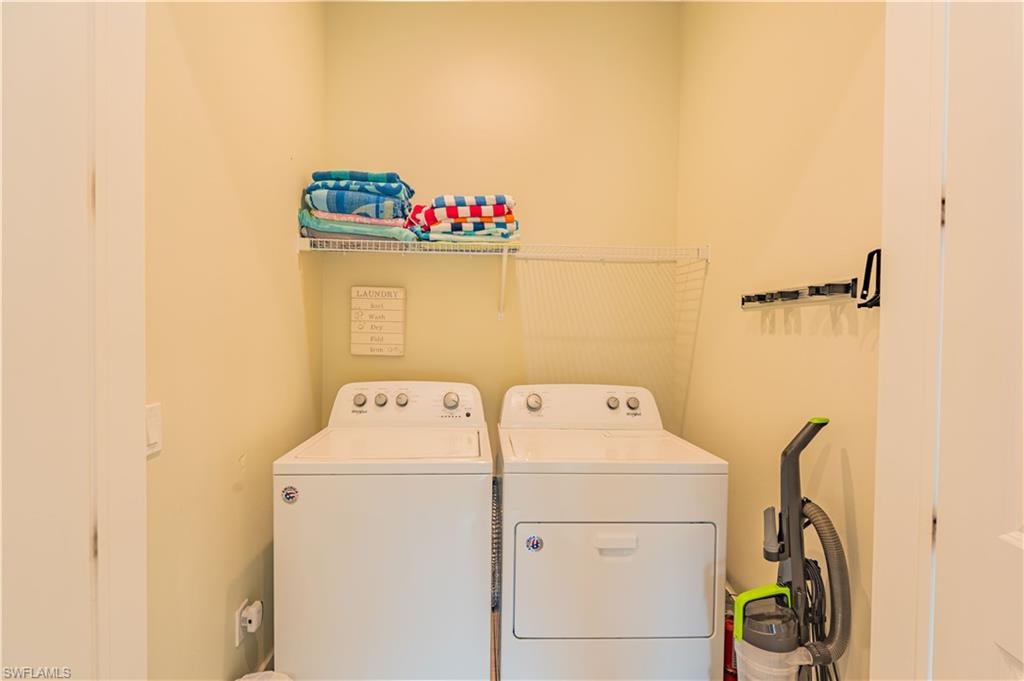 Dedicated laundry area featuring a washer and dryer, wire shelving, and wall-mounted organization hooks - Virtually Edited Image