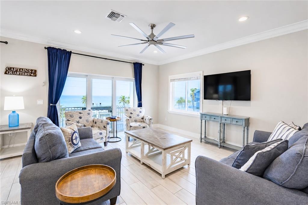 Living area featuring light wood-finish flooring, crown molding, and recessed lighting - Virtually Edited Image