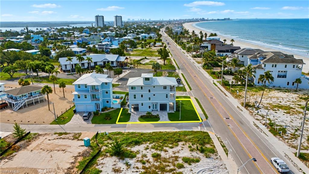 Coastal-style residence featuring multiple balconies, a ground-level garage, and a manicured lawn - Virtually Edited Image