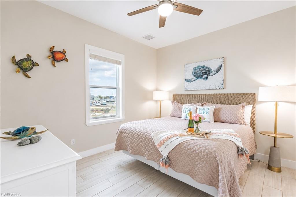 Bedroom featuring wood-finish flooring, a ceiling fan with integrated lighting, and a single window with blinds - Virtually Edited Image