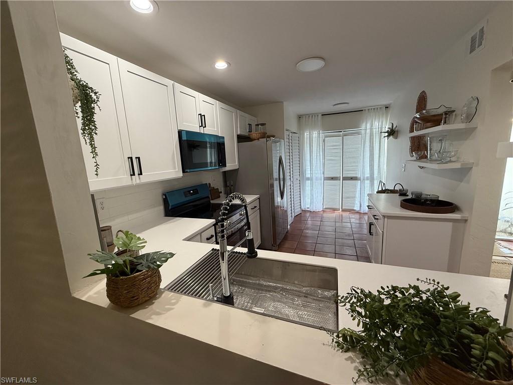 Contemporary kitchen featuring white cabinetry, a stainless steel sink with a high-arch faucet, a built-in microwave, and recessed lighting