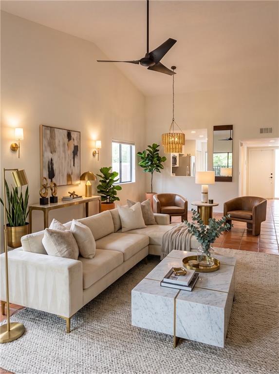 Vaulted ceiling living area featuring a modern ceiling fan, recessed lighting, wall sconces, and terracotta tile flooring
