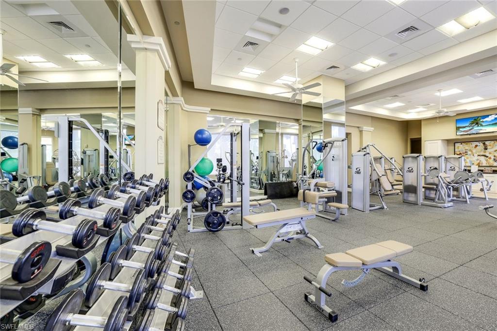 Gym featuring decorative columns, ceiling fan, and a drop ceiling