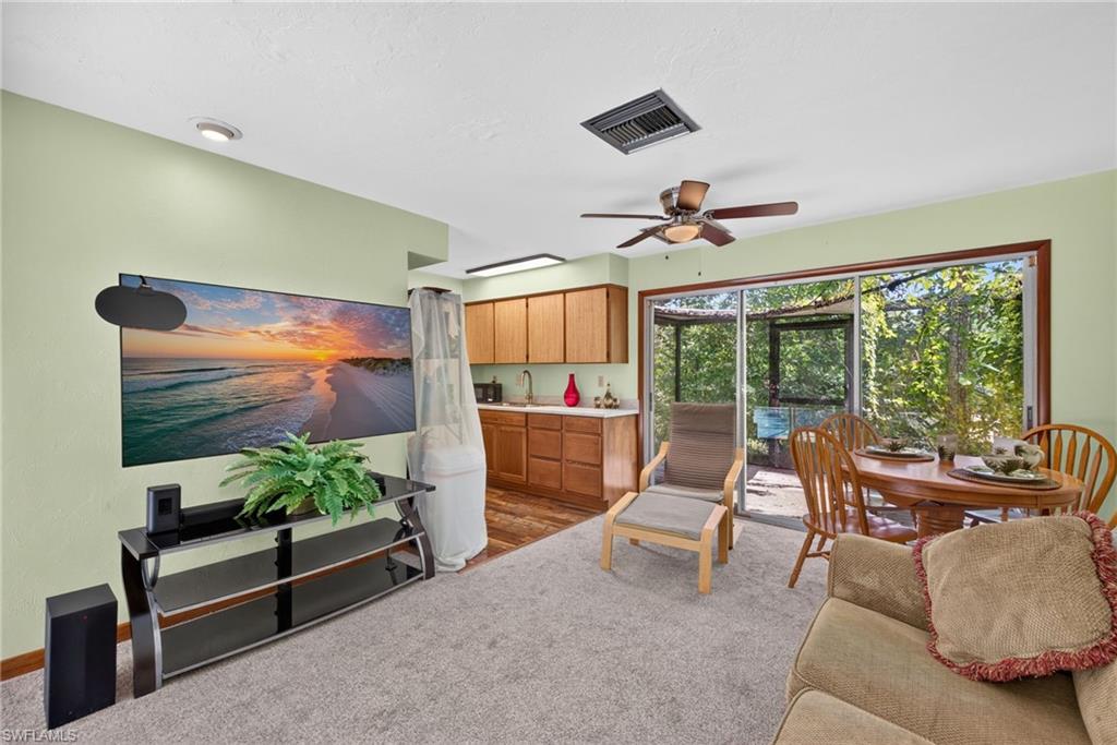 Living room with ceiling fan, kitchen, and sliding doors to the rear deck.