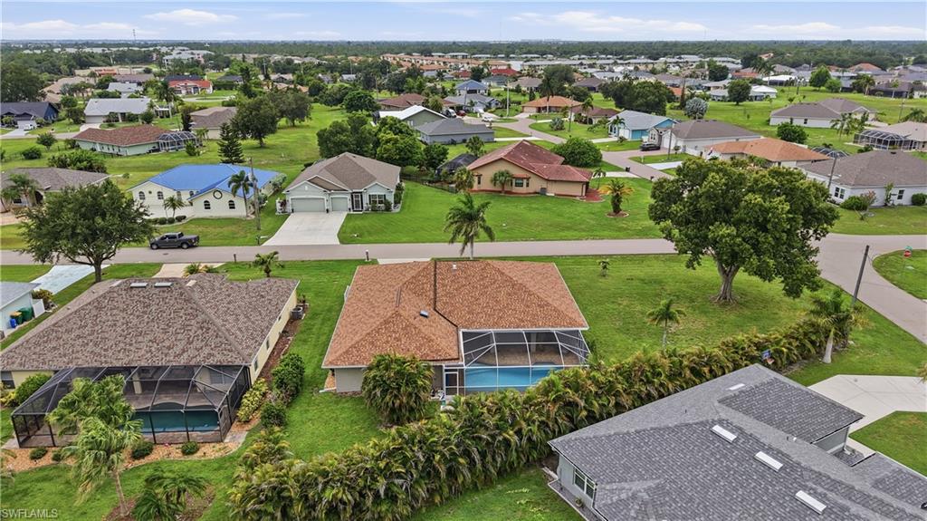 Aerial perspective showcasing a residential property with a screened pool enclosure and a shingle roof