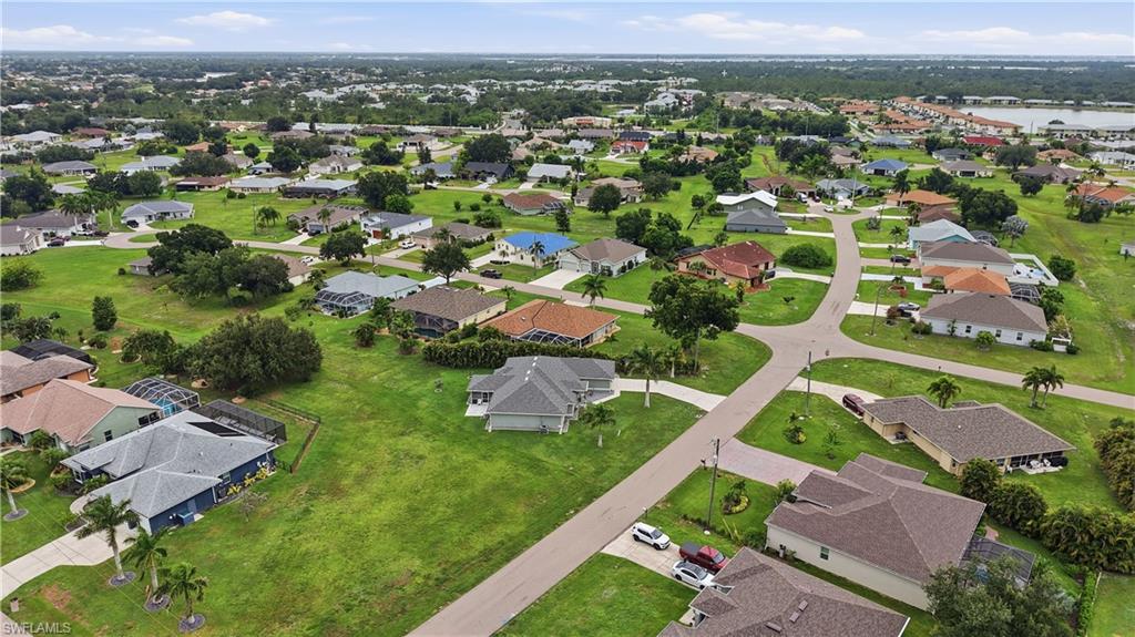 Aerial perspective showcasing a residential neighborhood with numerous single-story homes, expansive green spaces, and paved roads