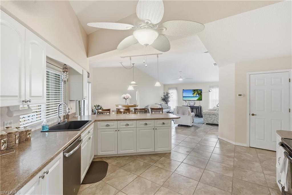 Kitchen featuring white cabinetry, a black single-basin sink, stainless steel dishwasher, and mottled brown countertops