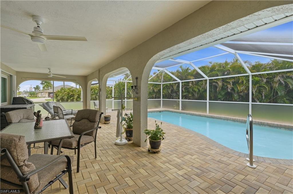 Screened pool and patio area featuring a freeform pool, brick paver decking, and arched patio supports
