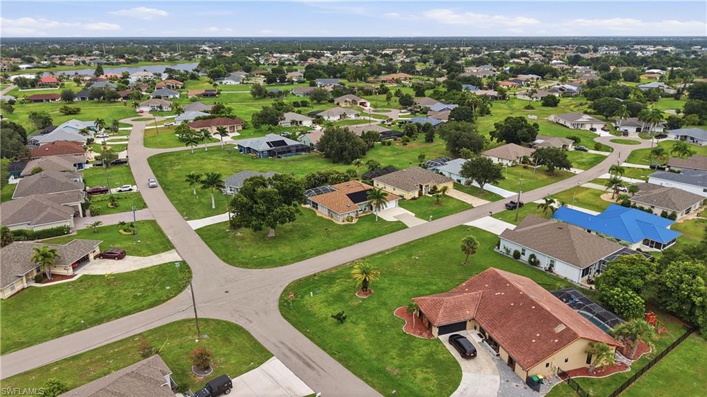 Expansive neighborhood featuring numerous single-story properties with mature trees, paved streets, and a distant body of water