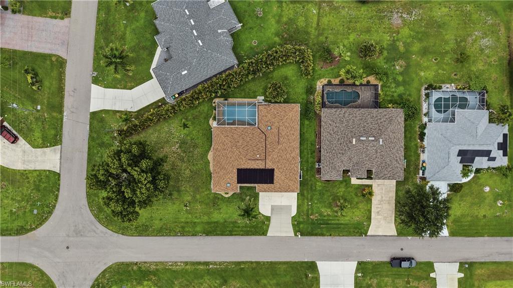 Aerial perspective of a property featuring a screened-in swimming pool and solar panels on the roof