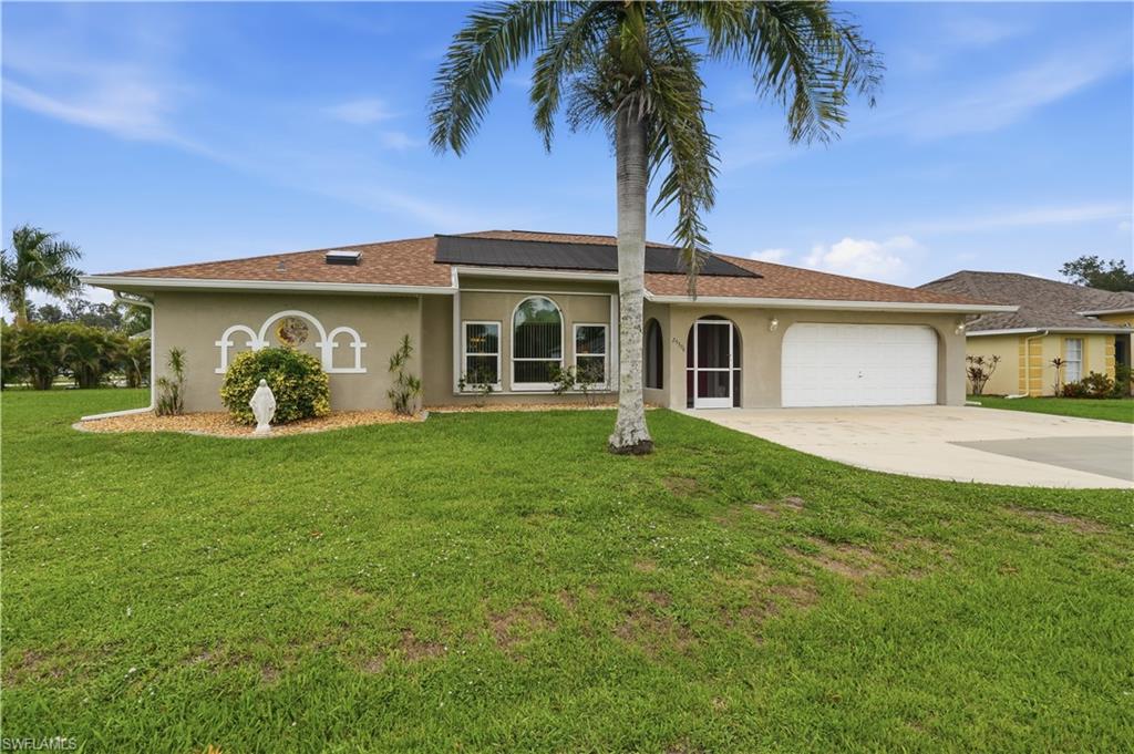 Stucco exterior residence featuring a brown shingle roof with solar panels