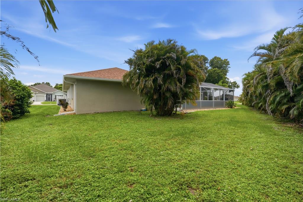 Expansive side yard featuring a lush lawn and established palm landscaping