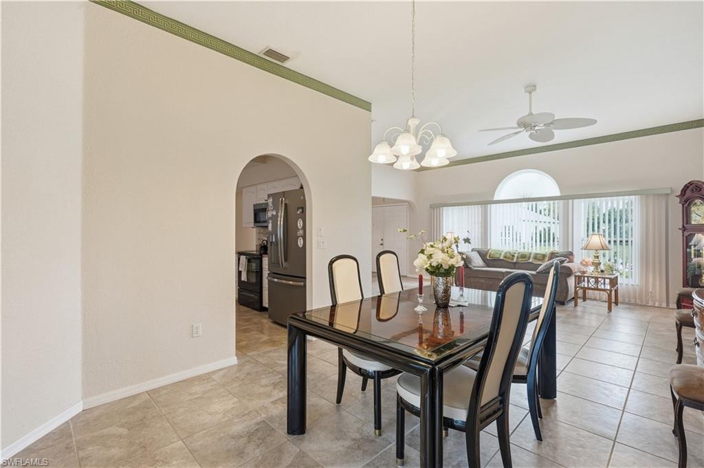 Tile flooring throughout, featuring an arched doorway, white chandelier, and vaulted ceilings