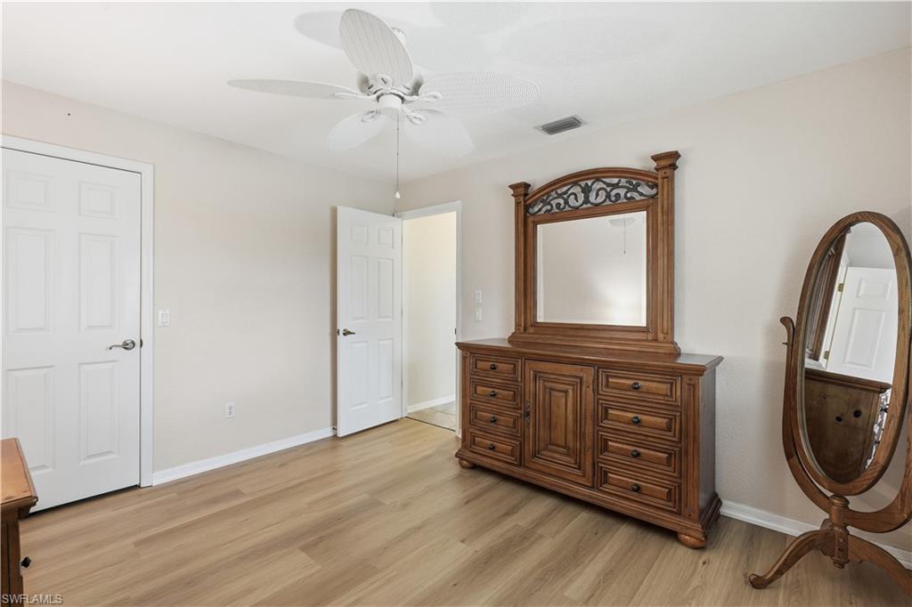 Spacious room featuring light wood-finish flooring, a ceiling fan, and crisp white trim
