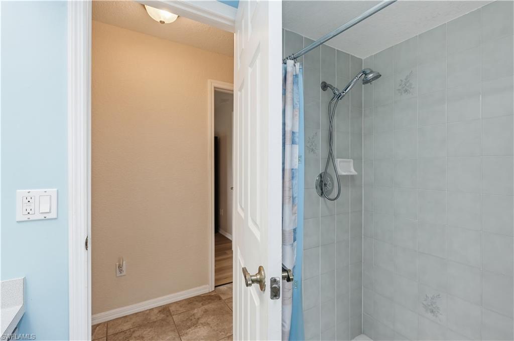 Shower stall featuring light gray tile surround, a chrome showerhead with handheld sprayer, and a built-in soap dish