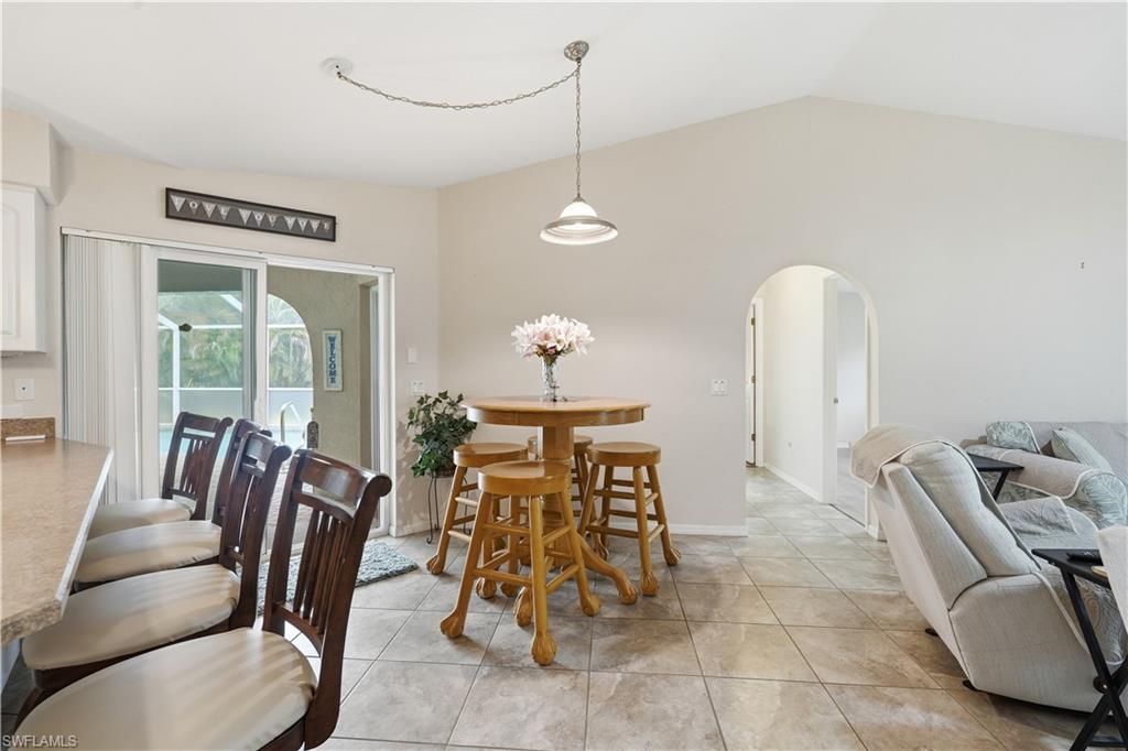 Open-concept interior featuring light gray wall paint, vaulted ceilings, and large format square floor tiles