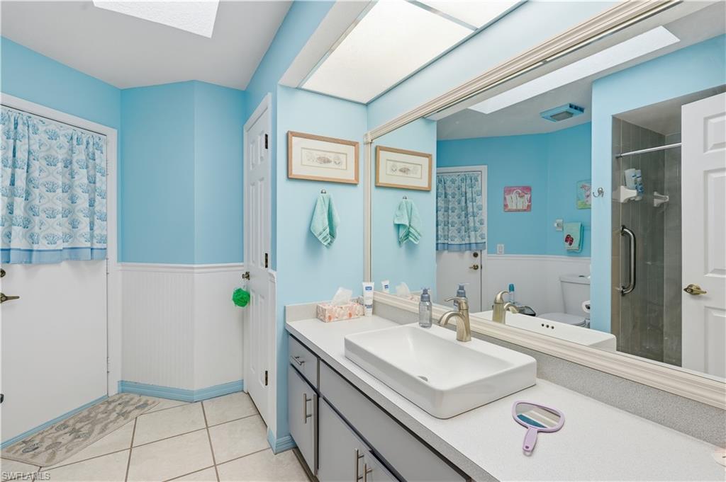 Bathroom featuring a large vanity with an integrated rectangular sink, a wide mirror, and an adjacent shower enclosure with a grab bar