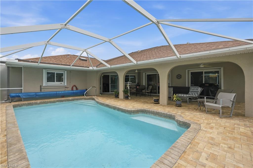 Screened pool enclosure featuring a rectangular pool with integrated steps, surrounded by a brick paver patio