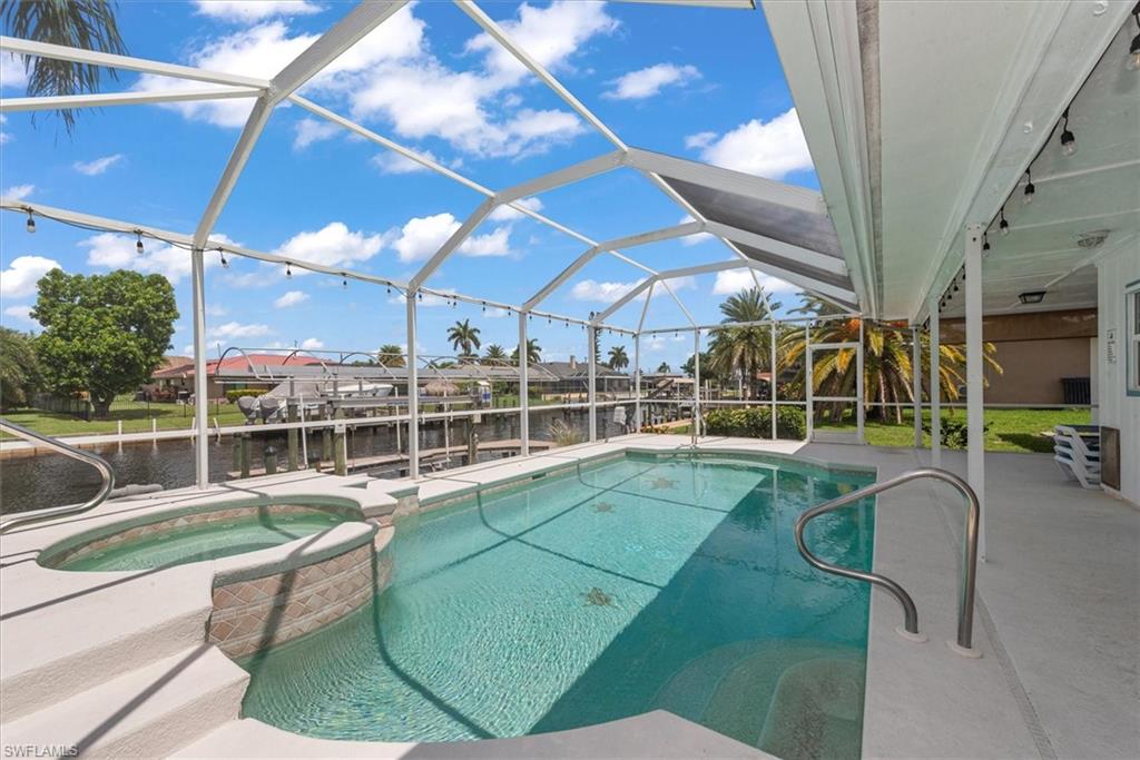 View of swimming pool with a patio area, a lanai, a pool with connected hot tub, and a water view