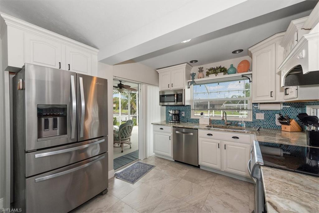 Kitchen with appliances with stainless steel finishes, backsplash, healthy amount of natural light, and white cabinetry