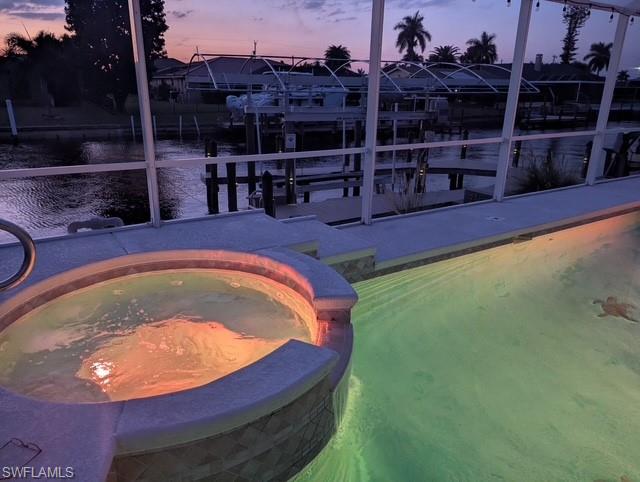 View of pool featuring a pool with connected hot tub, a water view, and boat lift