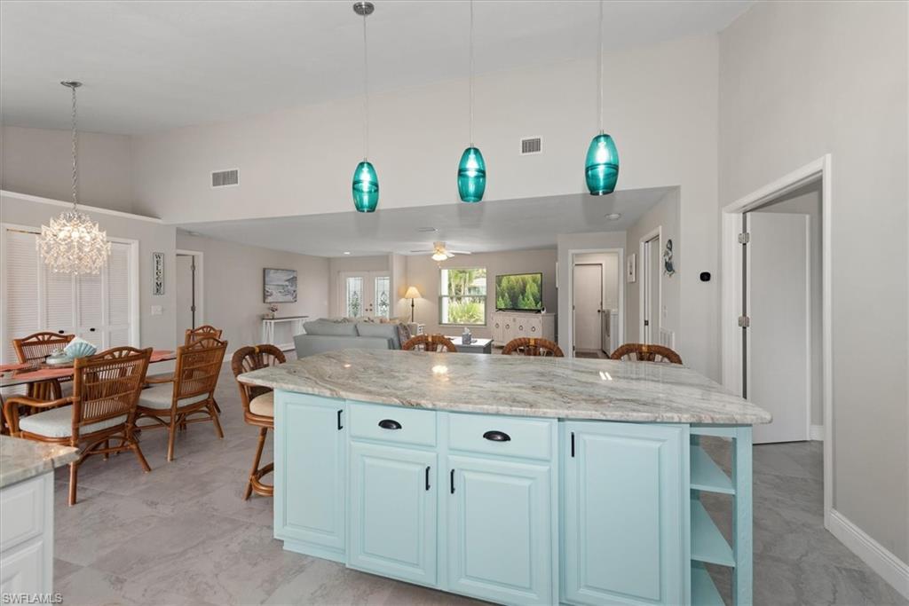 Kitchen featuring high vaulted ceiling, a kitchen bar, open shelves, a chandelier, and a kitchen island