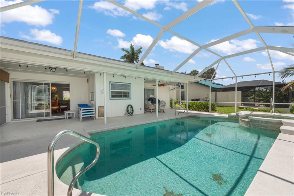 View of swimming pool with a patio area, a pool with connected hot tub, a ceiling fan, and glass enclosure