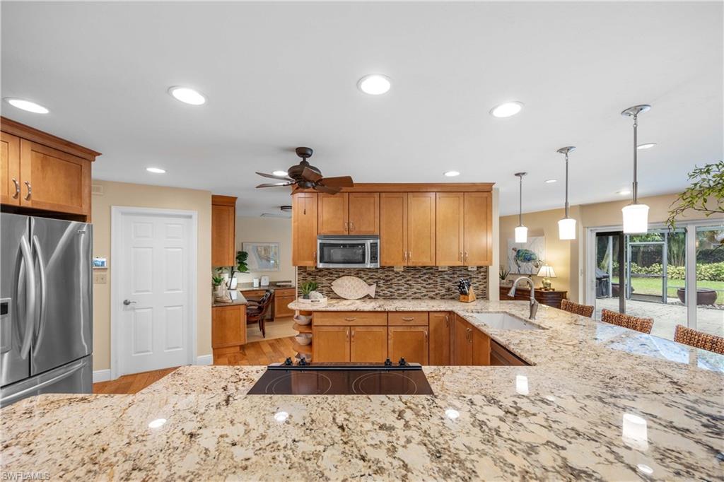 Kitchen featuring decorative light fixtures, light hardwood / wood-style floors, stainless steel appliances, sink, and ceiling fan