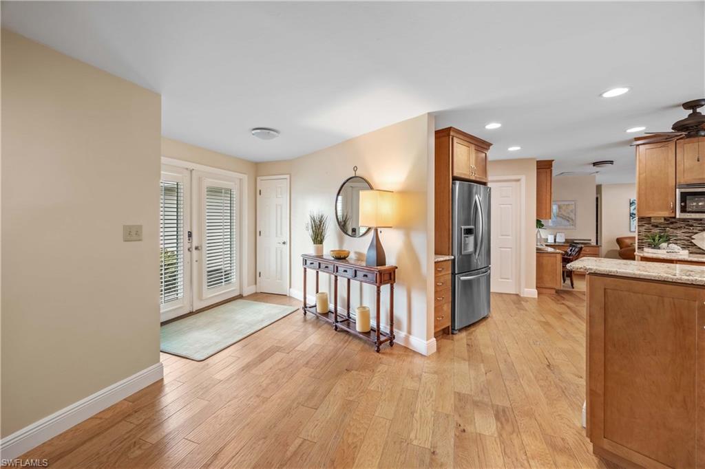 Entryway with french doors, a stone fireplace, ceiling fan, and light hardwood / wood-style floors
