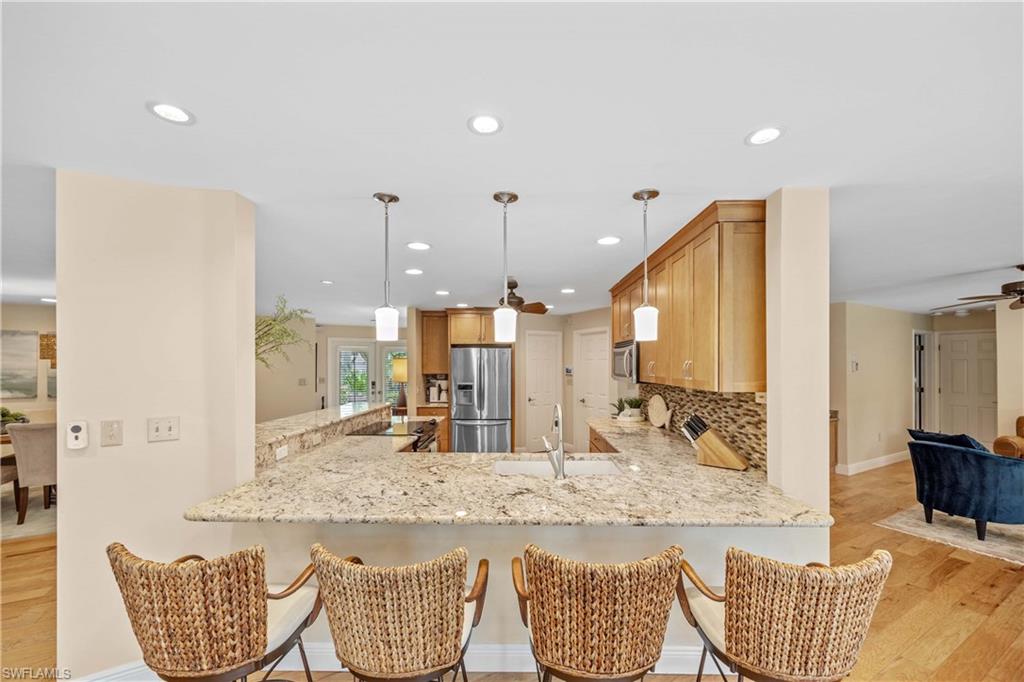 Kitchen featuring backsplash, appliances with stainless steel finishes, sink, ceiling fan, and light wood-type flooring