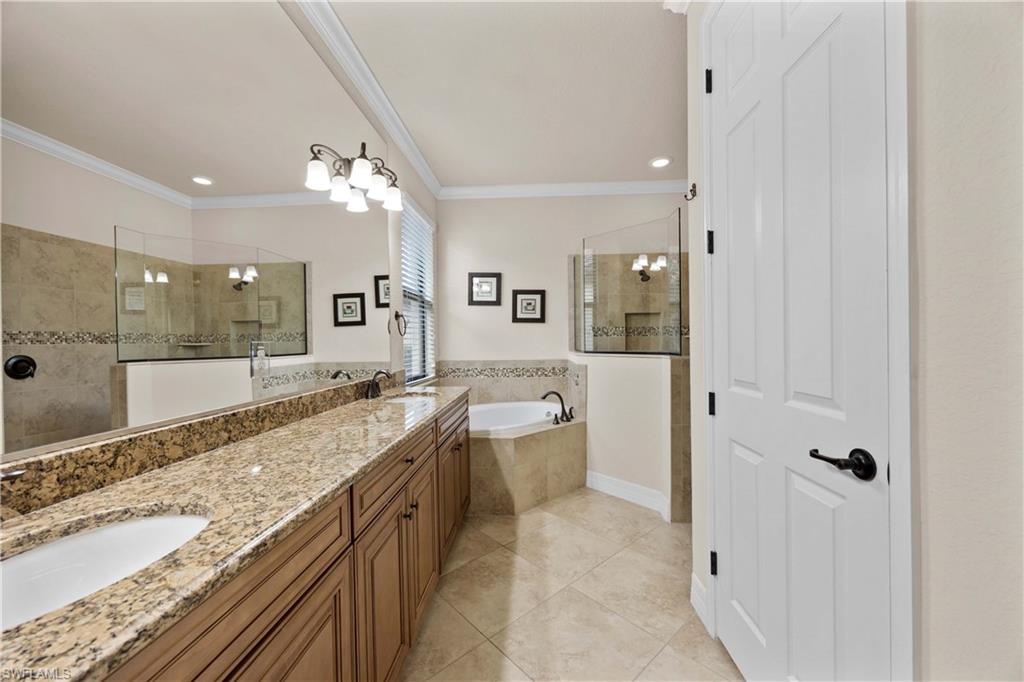 Bathroom with tile flooring, ornamental molding, large vanity, double sink, and plus walk in shower