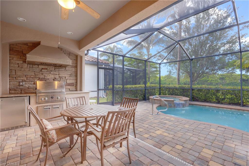 View of swimming pool with ceiling fan, an in ground hot tub, grilling area, a patio area, and glass enclosure