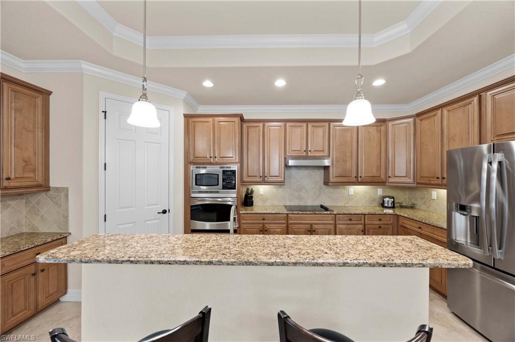 Kitchen with appliances with stainless steel finishes, crown molding, a center island, and a raised ceiling