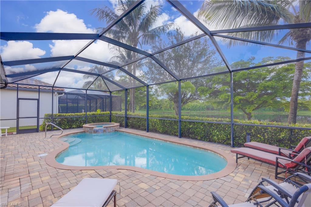 View of swimming pool featuring a patio, glass enclosure, and an in ground hot tub