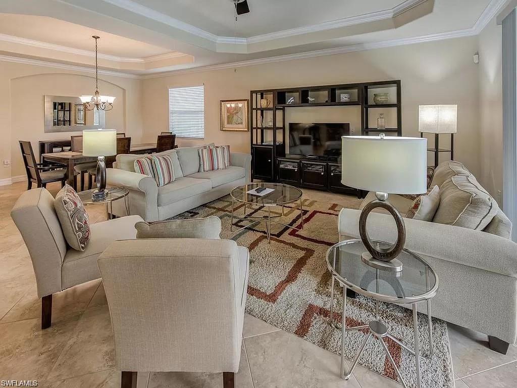 Living room with a chandelier, crown molding, a raised ceiling, and light tile patterned floors