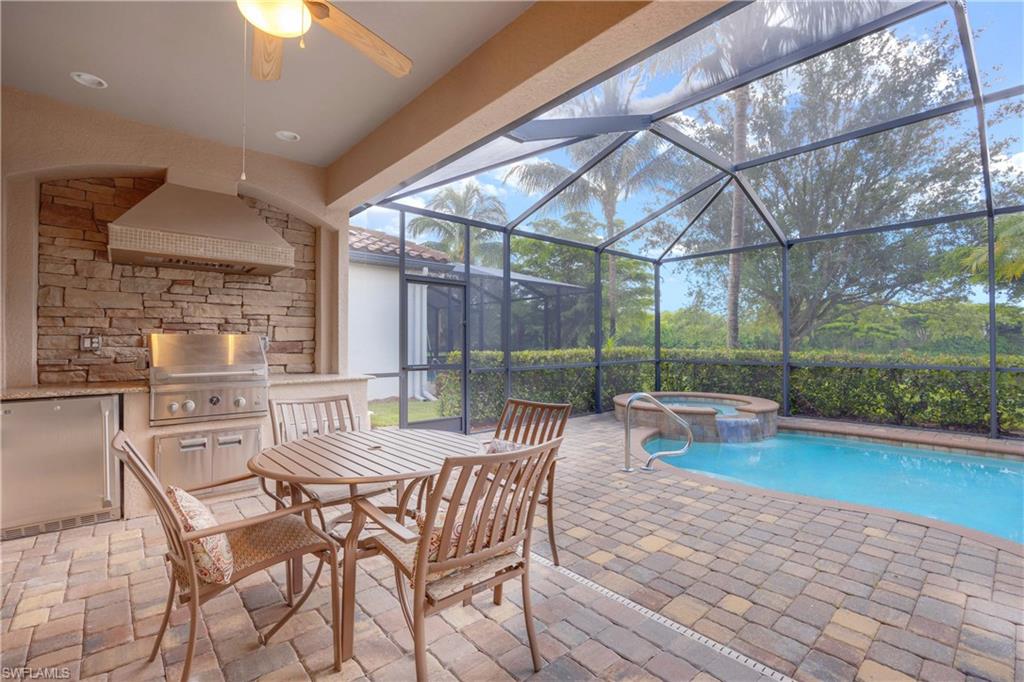 View of pool with ceiling fan, an in ground hot tub, a patio area, a grill, and a lanai