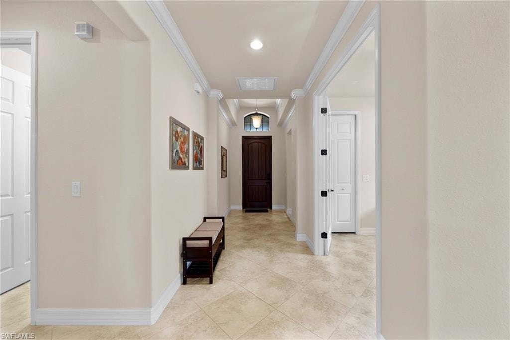 Hallway with ornamental molding and light tile floors