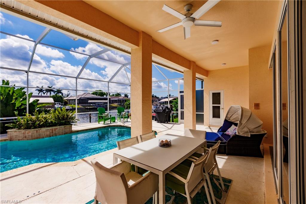 View of swimming pool with a lanai, ceiling fan, a water view, and a patio