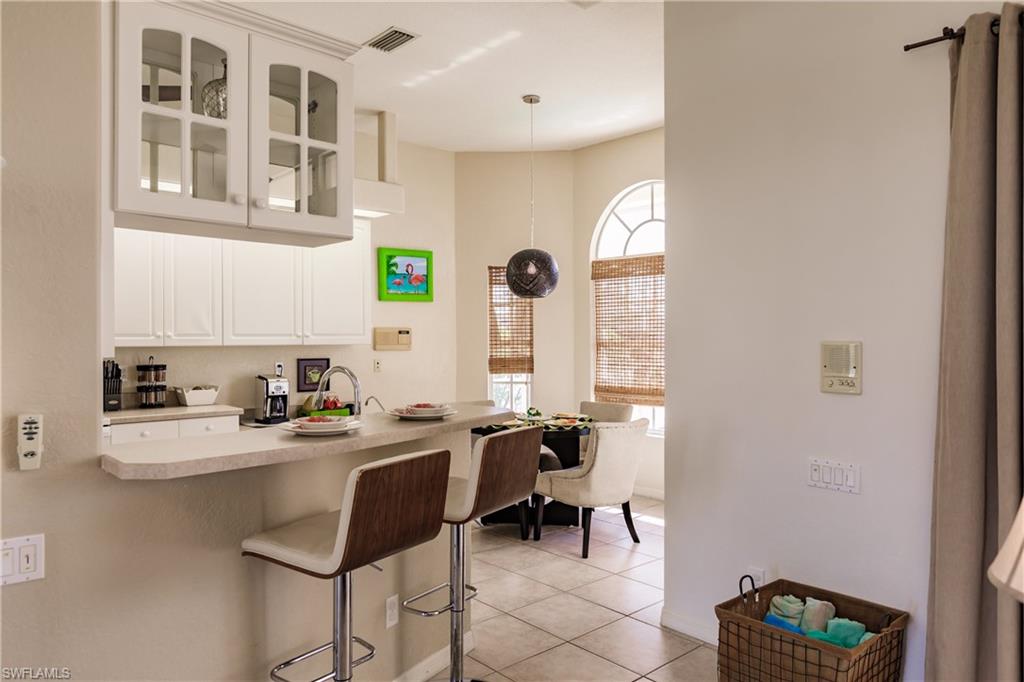 Kitchen featuring a kitchen bar, kitchen peninsula, pendant lighting, light tile patterned floors, and white cabinets