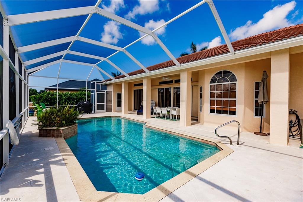 View of swimming pool with area for grilling, a patio, glass enclosure, and ceiling fan